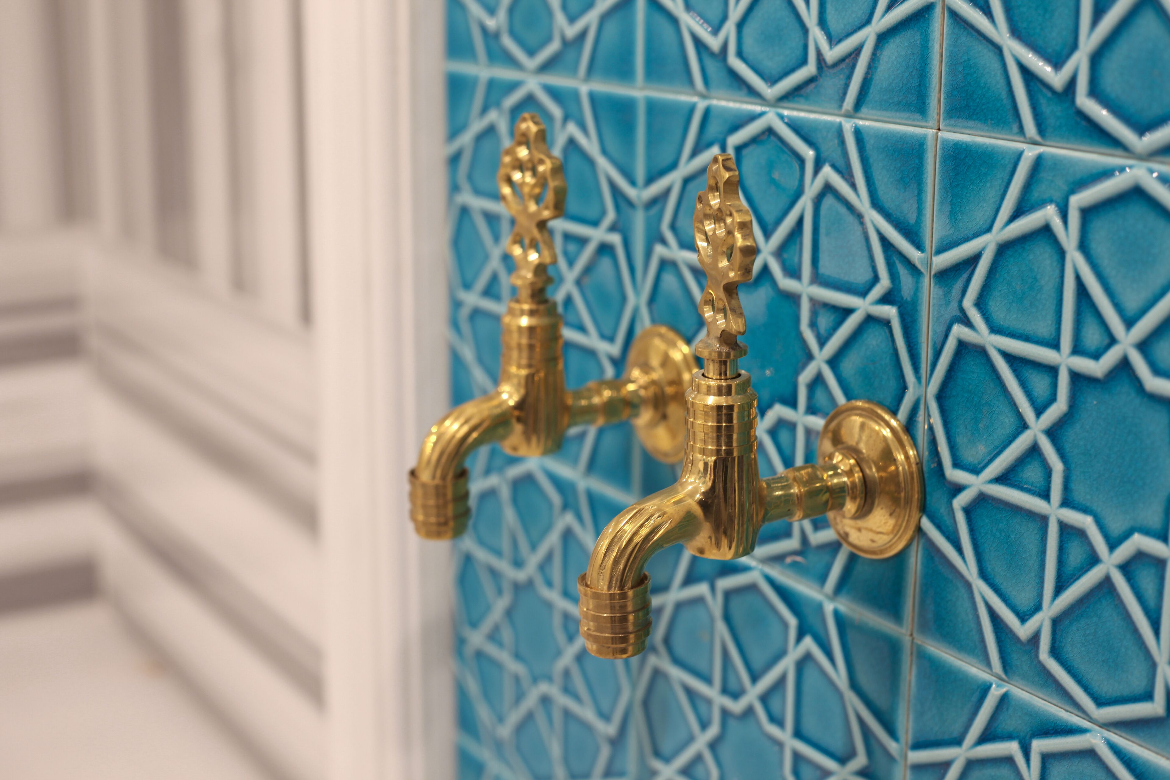 A bathroom with blue patterned tiles and gold fixtures.