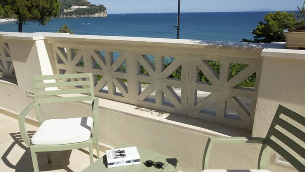 A balcony with two green chairs and a small table, overlooking a coastal view with a clear sky. - Chiaror di Mare (Gaeta)