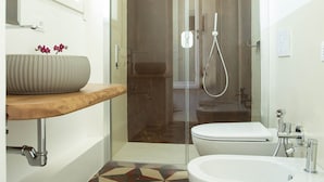 A modern bathroom with a glass-enclosed shower, a freestanding bathtub, and a sink with a decorative vase. - Chiaror di Mare (Gaeta)