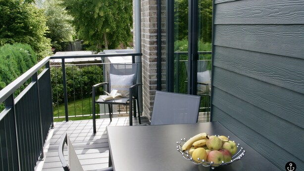 En balkon med et bord, stole og en skål med frugt.