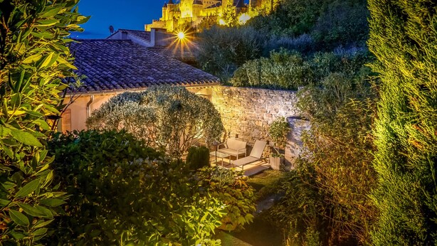 A historic castle with a stone wall and a tiled roof, surrounded by lush greenery. - GITES GRAND CANISSOU (Carcassonne)