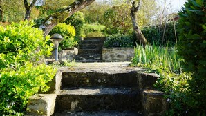 A stone staircase leading up to a house, surrounded by lush greenery and a lamp post. - GITES GRAND CANISSOU (Carcassonne)