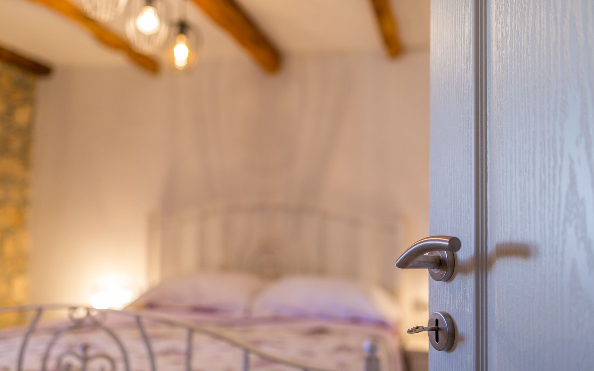 A bedroom with a bed, a door, and a light fixture.