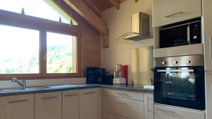 Una cocina con gabinetes blancos, una campana de acero inoxidable, un microondas y un horno.