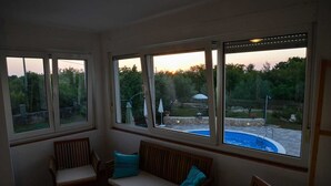 Une véranda avec vue sur une piscine et un jardin.
