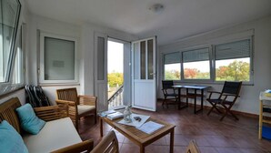 Une vaste terrasse dotée d’une table et de chaises en bois, d’un canapé et d’une porte-fenêtre coulissante donnant sur un balcon.