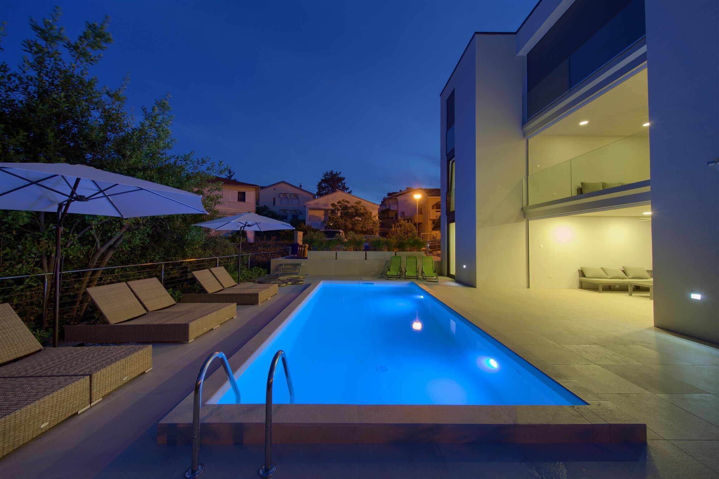 Une piscine entourée de bâtiments modernes, avec des chaises longues et des parasols.