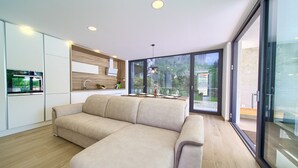 A modern kitchen with built-in appliances, a large window, and a seating area with a sofa.