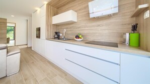 A modern kitchen with wooden wall panels, white cabinetry, and a built-in microwave.