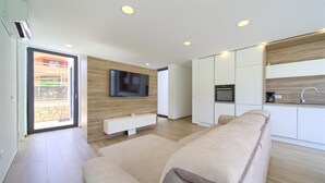 A modern living room with a flat-screen TV, a built-in bench, and a sofa.