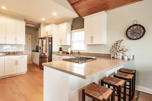 A kitchen with white cabinets, a stainless steel refrigerator, a wooden ceiling, and a clock on the wall. - 5 Min Walk to Beach & Community Pool; Views of Lagoon & Ocean from Rooftop Deck; Great for Families! (Isle of Palms)