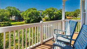 Een veranda met uitzicht op een meer, bomen en huizen in de verte.