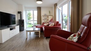 Uma sala de estar moderna com televisão de tela plana, sofá de couro vermelho e uma mesa de centro.