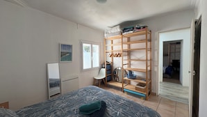 Une chambre à coucher comprenant un lit, une armoire, un radiateur, une affiche et une porte donnant sur une autre pièce.