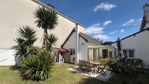Une maison avec un patio, une table en bois et des chaises.