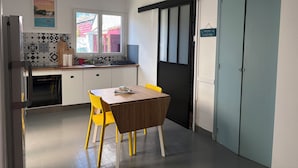 Une cuisine avec une table à manger, des chaises jaunes, une fenêtre et une porte.