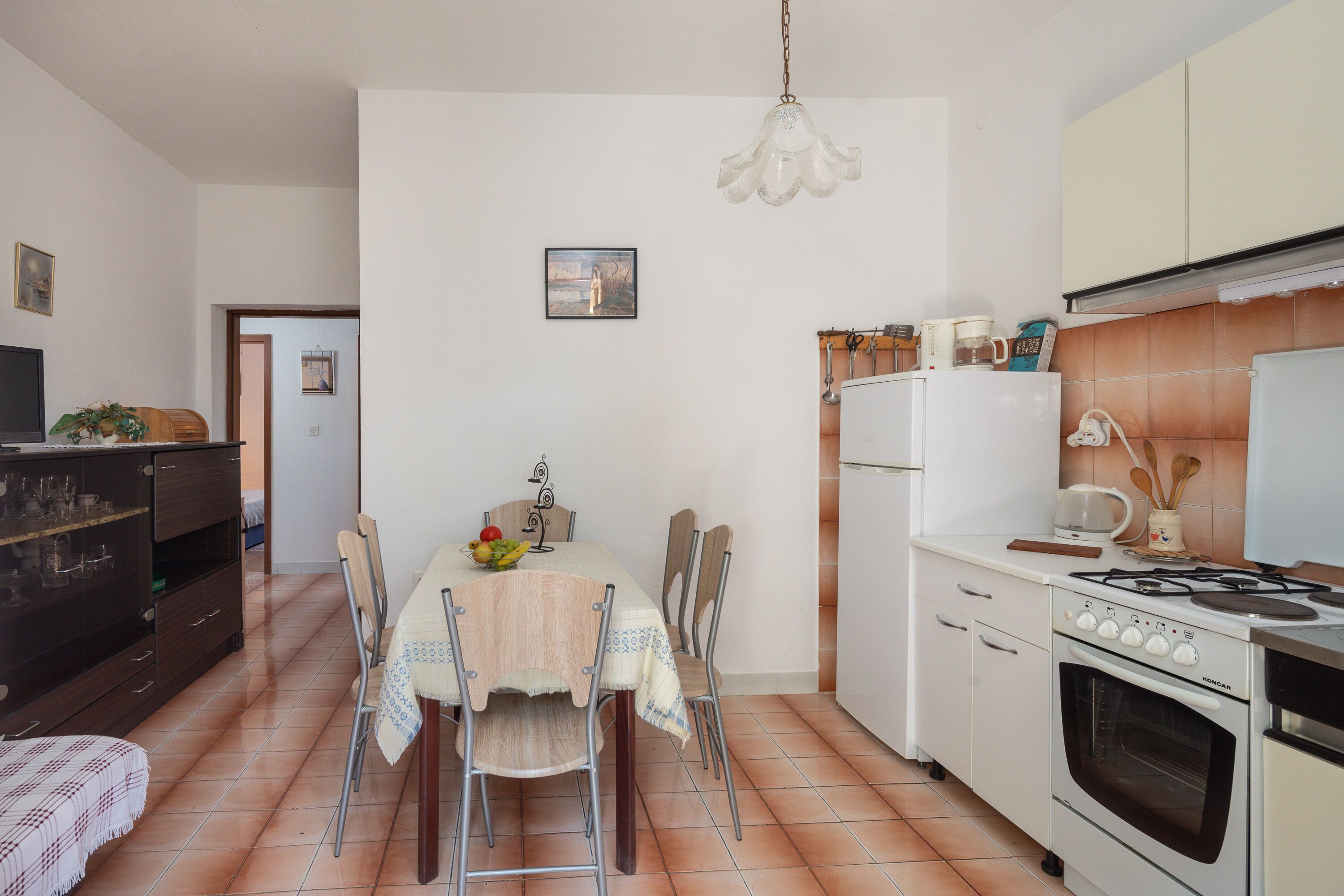 A compact kitchen with a dining table, chairs, a stove, and a refrigerator.