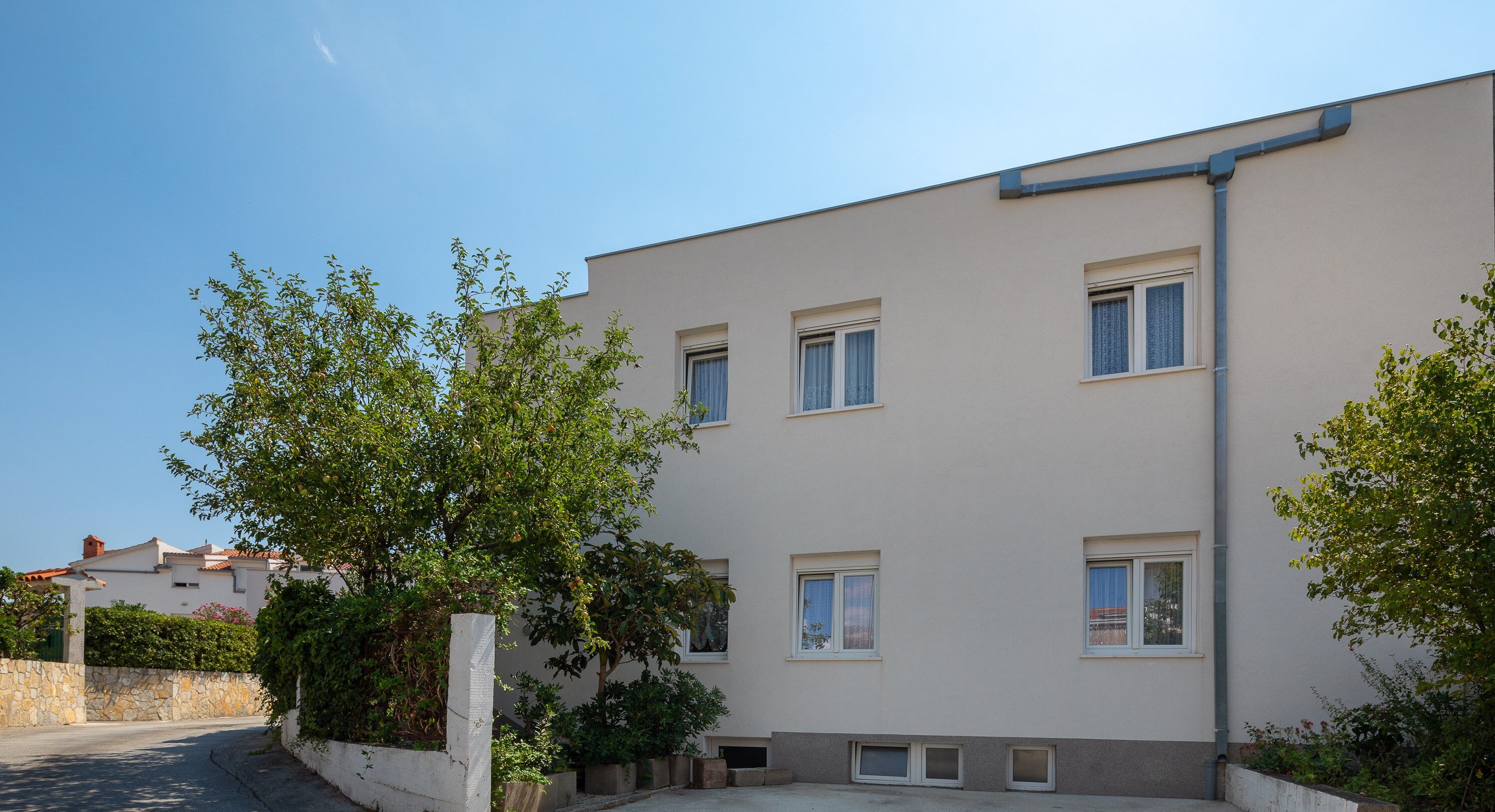 Ein modernes, zweistöckiges Gebäude mit Flachdach, zahlreichen Fenstern und befestigter Auffahrt.