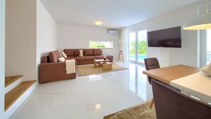 A modern living room with a brown sofa, a coffee table, and a TV mounted on the wall.