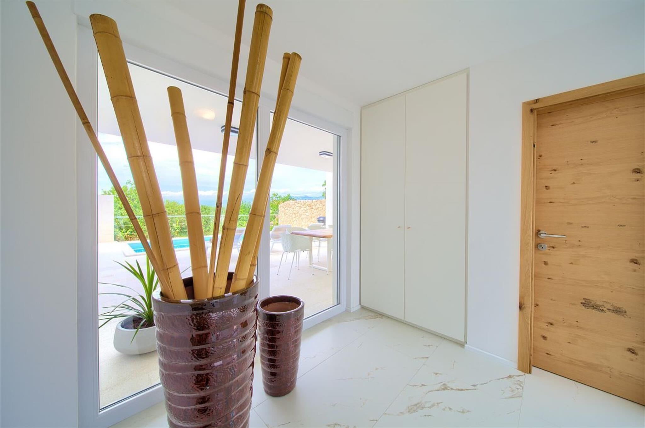 A modern room with a large sliding glass door leading to an outdoor area, a wooden door, and a potted plant.