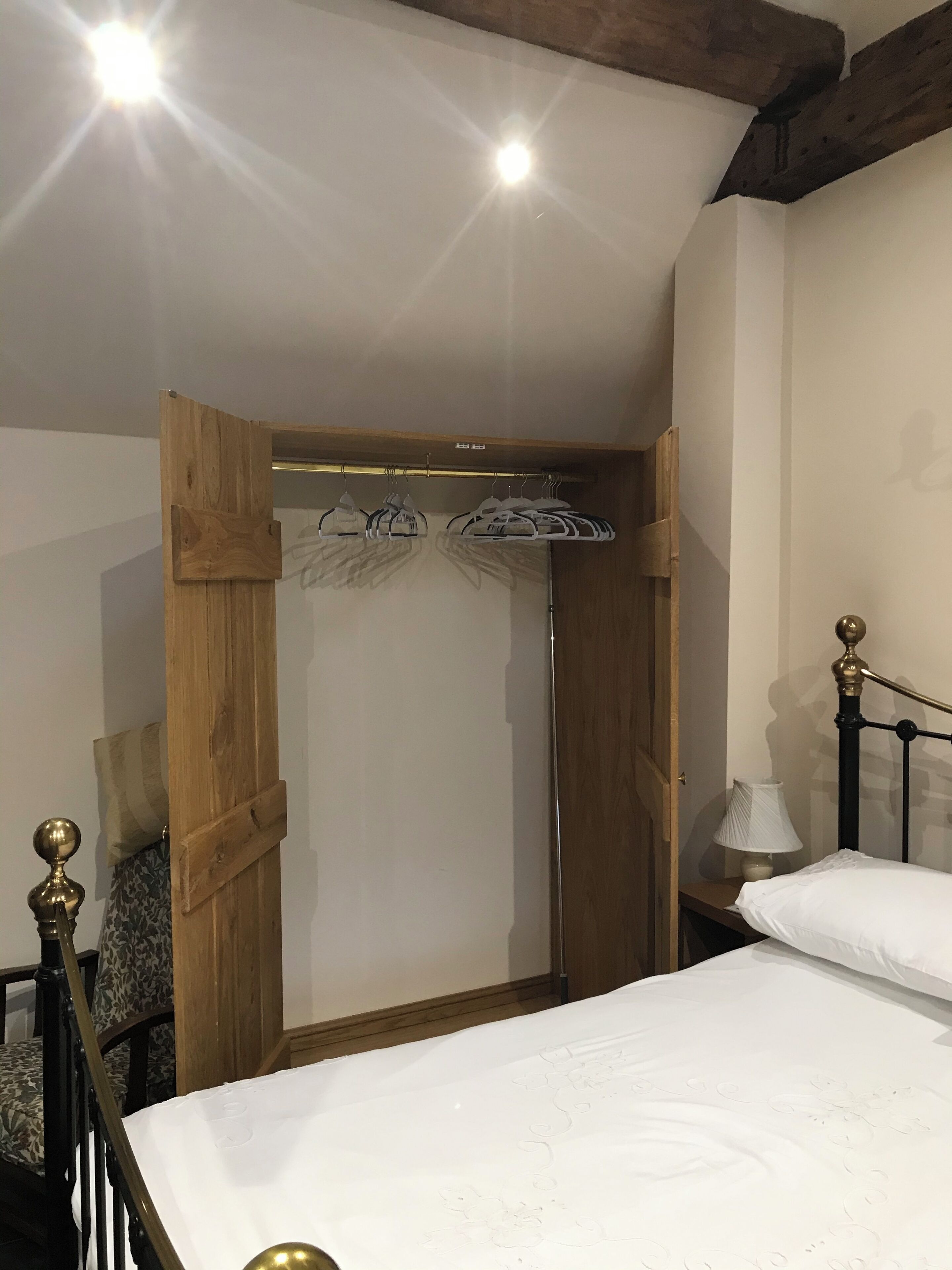 Un lit superposé avec une structure en bois et des éléments décoratifs en métal, un matelas blanc et une tête de lit ornée d’un bouton décoratif.