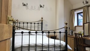 A bedroom with a black metal bed frame, a wooden door, a desk with a chair, and a window with curtains. - Nuneaton - Cottage - Sleeps 2 - Parking - Garden (Nuneaton)