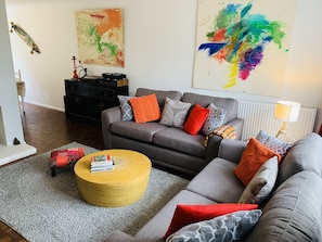 A living room with a grey sofa, a round coffee table, and a black cabinet.