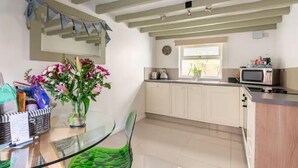 Una cocina moderna con armarios blancos, un microondas y un ventanal.