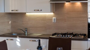 Une cuisine moderne dotée d’un évier en acier inoxydable, d’une cuisinière à gaz et d’un dosseret en bois.
