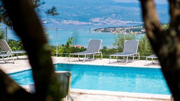 Une piscine avec trois chaises longues et vue sur une ville côtière.