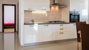 Une cuisine moderne avec des meubles blancs, une cuisinière à gaz et un four encastré.