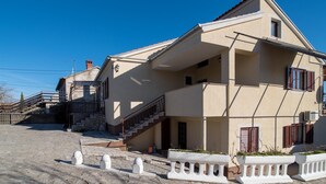 Un bâtiment à deux étages doté d’un balcon, d’un escalier menant à l’étage supérieur et d’une petite fenêtre avec des volets.