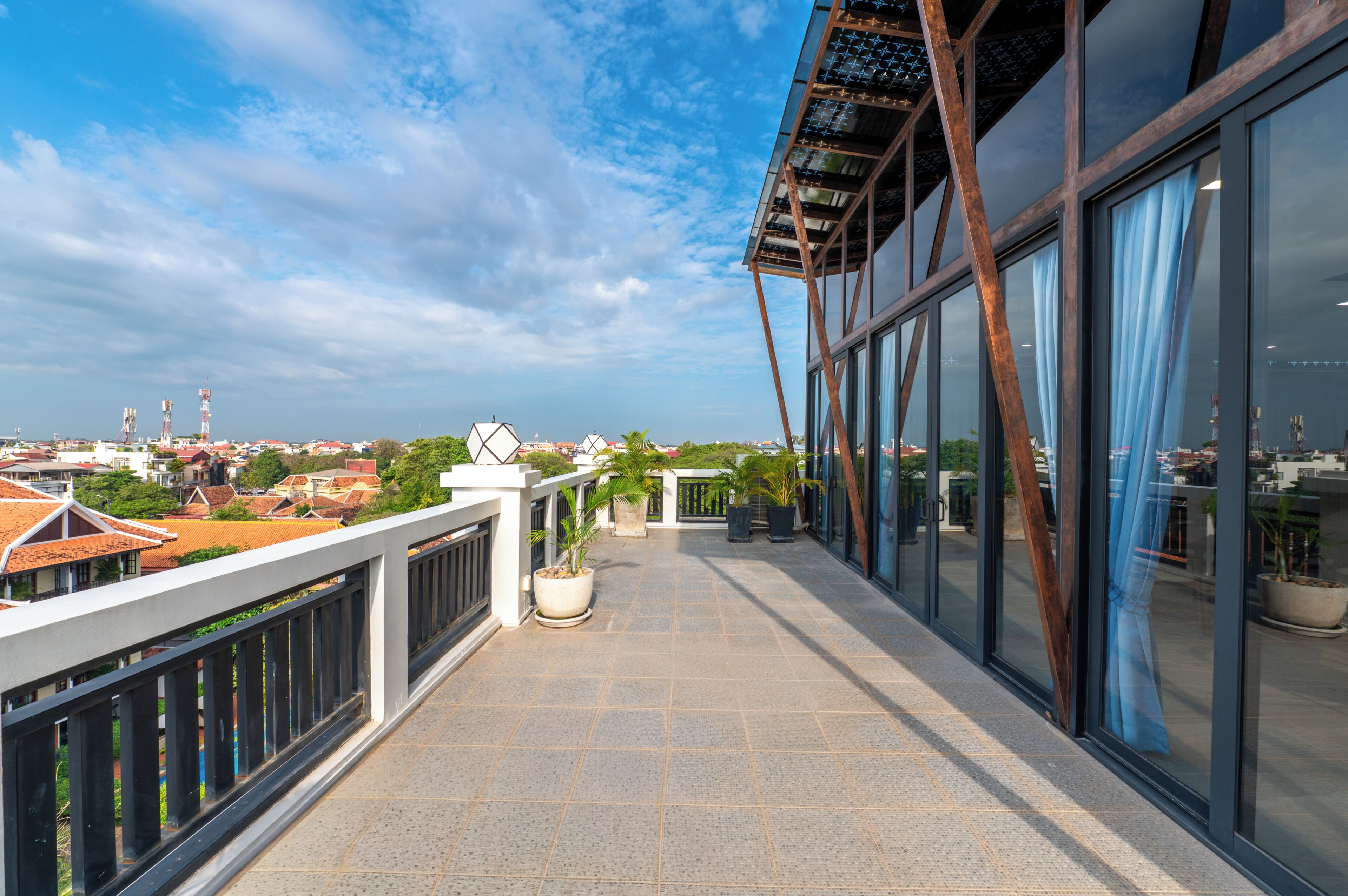 A balcony with a view of a cityscape, potted plants, and a modern building facade.
