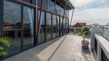 Um edifício moderno com grandes janelas de vidro, terraço revestido e um vaso de planta.