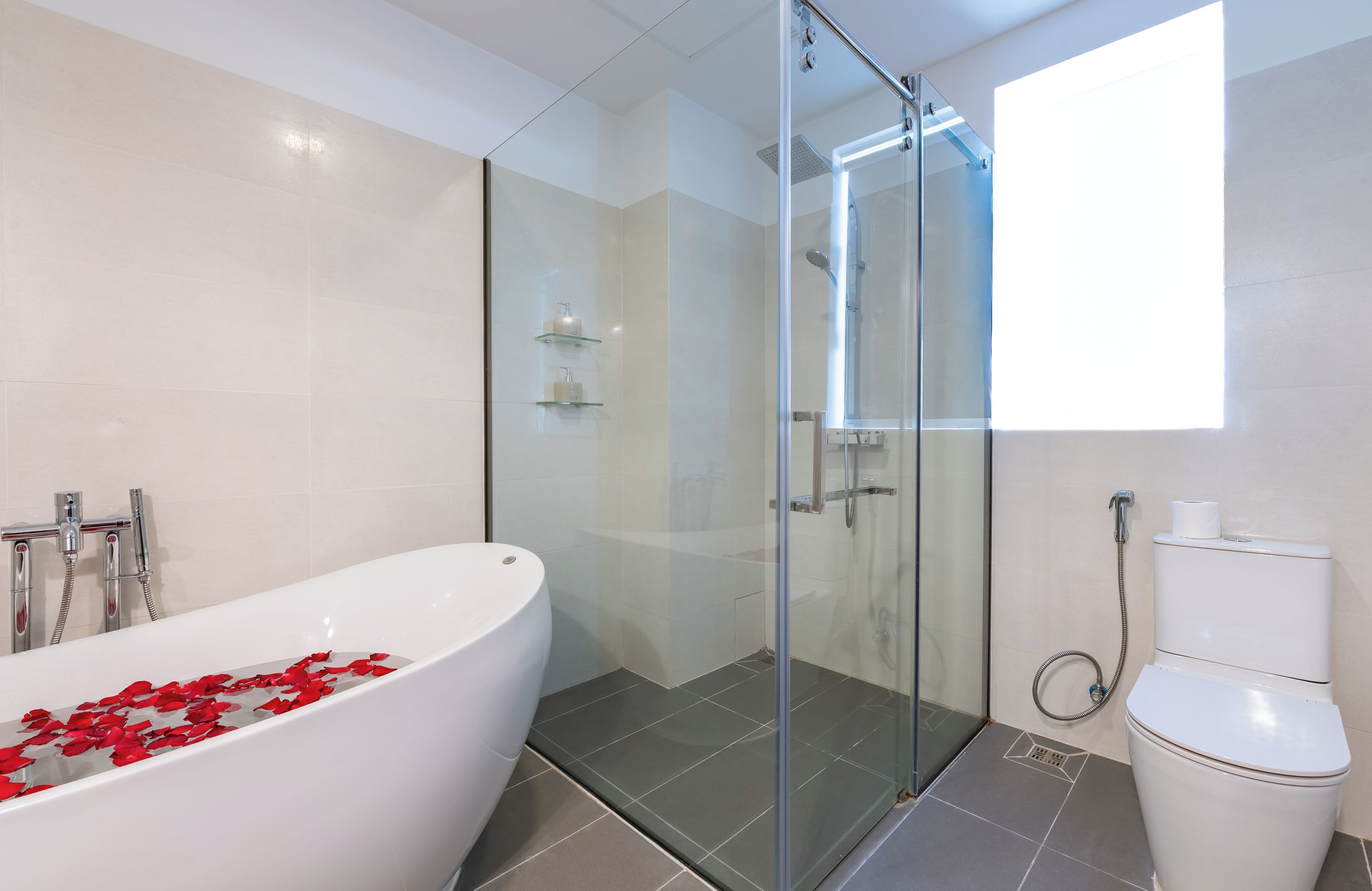 A modern bathroom with a glass-enclosed shower, a freestanding bathtub, and a toilet.