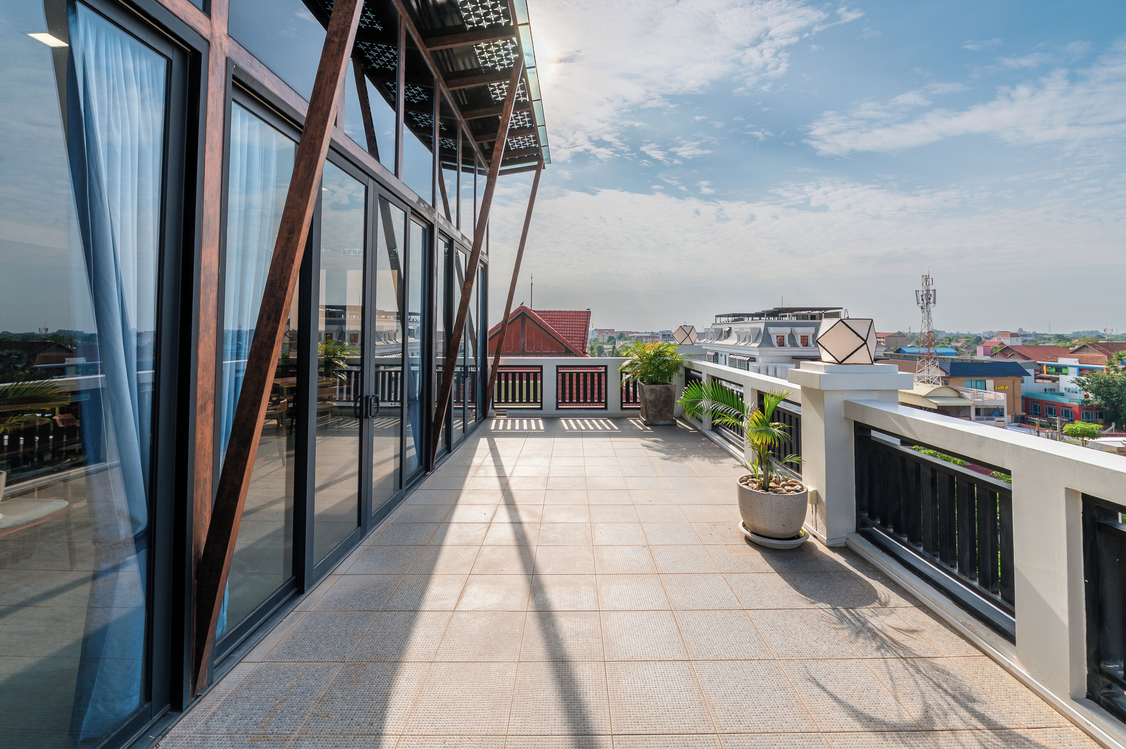A modern building with large windows, a balcony with potted plants, and a clear view of the surrounding cityscape.