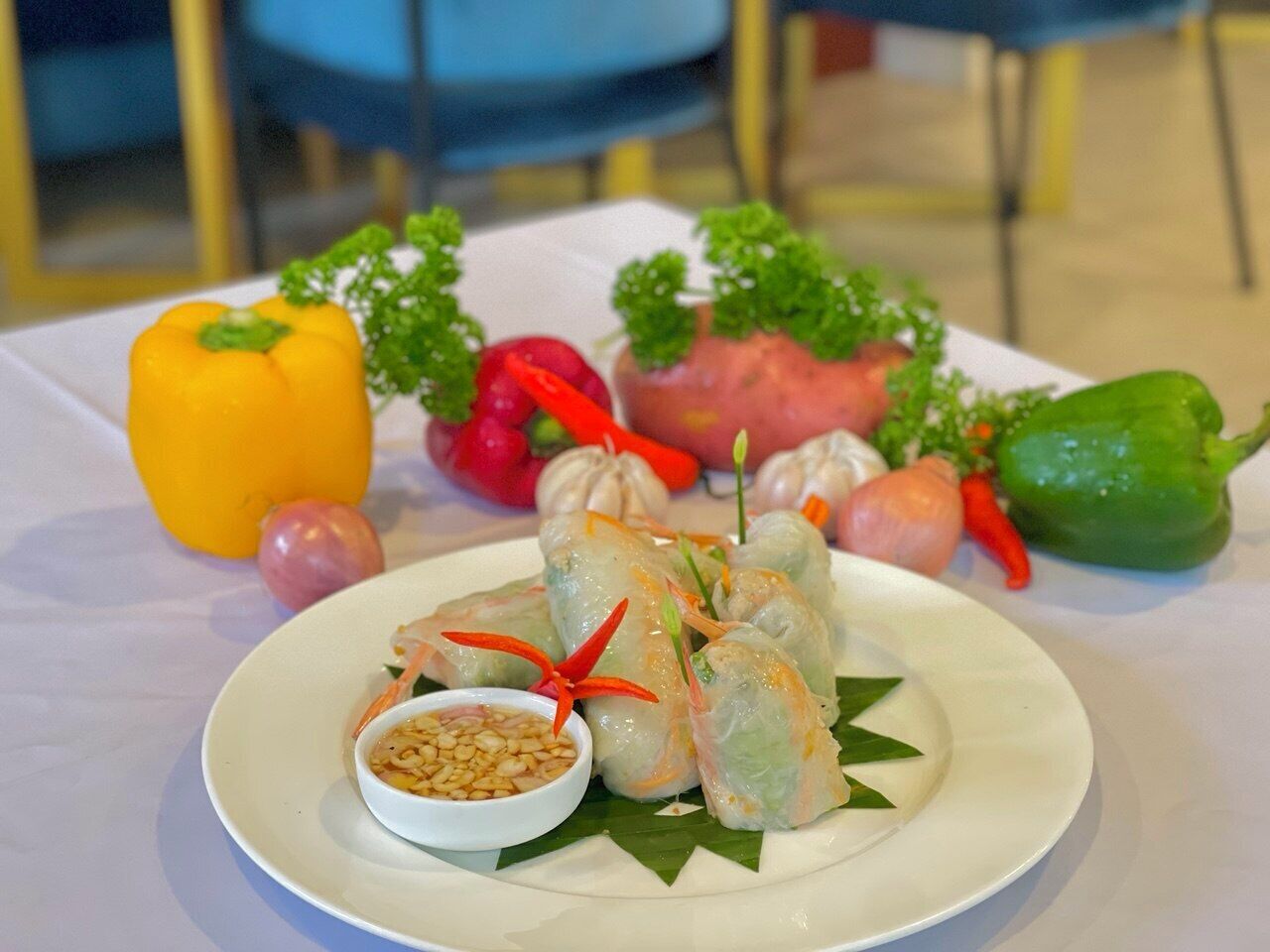 Une assiette de rouleaux de printemps vietnamiens, accompagnés d’un petit bol de sauce pour tremper et de quelques garnitures.