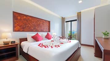 A hotel room with a bed, a nightstand, a digital clock, a large window with a view, and a potted plant.