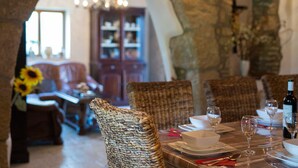 A dining area with wicker chairs, a table set for two with wine glasses and plates, and a view of a living room with a sofa and a cabinet in the background. - Villa Magdalea With Swimming Pool And Seaview (Hlapa (Krk))