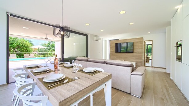 Una cocina moderna con comedor, un ventanal grande y un televisor montado en la pared.