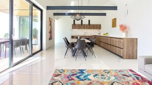 Una cocina moderna con una isla de madera, sillas negras y una alfombra colorida.
