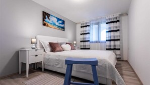 Una camera da letto con un letto, comodini, una lampada, un quadro e tende a righe.
