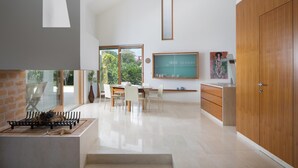 A spacious kitchen with a dining area, large windows, and a wooden cabinet. - Exclusive and modern Casa Vidmar with a large swimming pool (Klimno (Krk))