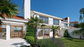 A modern two-story house with a balcony, a patio with chairs, and a well-maintained garden. - Exclusive and modern Casa Vidmar with a large swimming pool (Klimno (Krk))