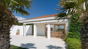 A modern house with a covered patio, a dining area with wooden furniture, and a white exterior. - Exclusive and modern Casa Vidmar with a large swimming pool (Klimno (Krk))