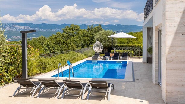 A swimming pool with lounge chairs and a hanging chair, surrounded by greenery and a view of mountains. - Villa Zarra with heated pool, jacuzzi, sauna and Seaview (Klimno (Krk))