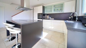A modern kitchen with a central island, bar stools, a microwave, and a sink. - Residencia La Famiglia with heated swimming pool and beautiful Seaview (Klimno (Krk))
