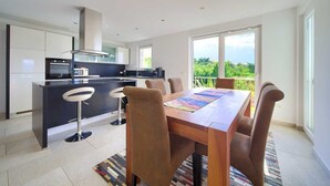 A modern kitchen with a dining area, large windows, and a view of greenery. - Residencia La Famiglia with heated swimming pool and beautiful Seaview (Klimno (Krk))