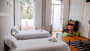 Une chambre d’hôtel avec deux lits, un plancher en bois, un bureau, une chaise et une vue sur l’extérieur.