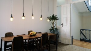 Un espace repas avec une table en bois, des chaises noires et des lampes suspendues.